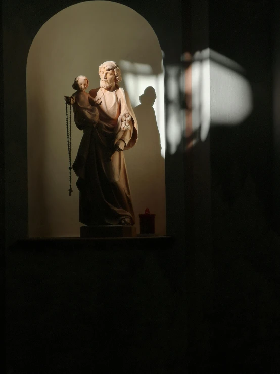 a statue of a woman holding a child, by Jan Tengnagel, unsplash, mannerism, shadow of catholic church cross, indoor scene, orthodox saint christopher, backlighted