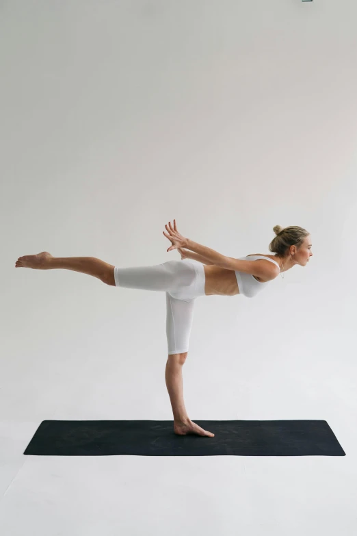 a woman doing a yoga pose on a yoga mat, by Carey Morris, arabesque, sleek white, hero pose, standing, 0