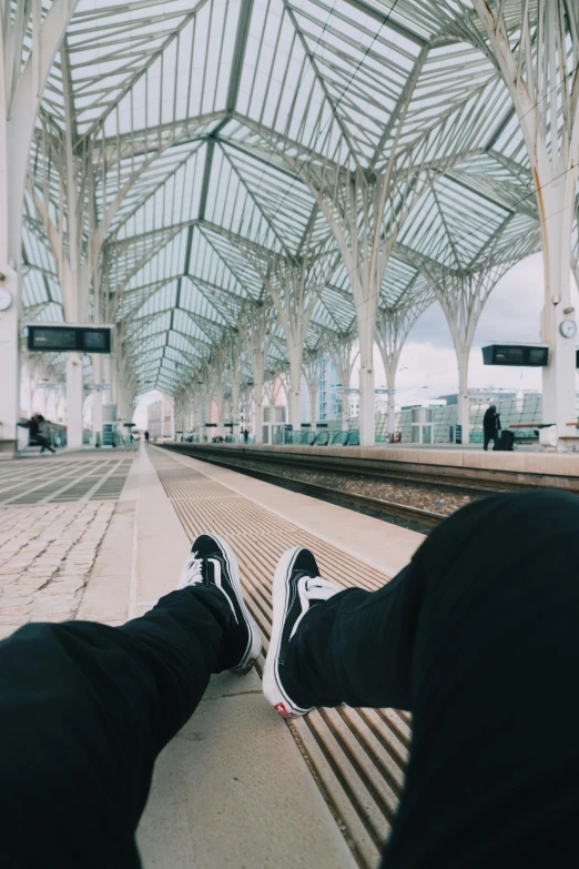 a person sitting on a bench at a train station, pexels contest winner, hyperrealism, lisbon, legs spread, low quality photo, trending on vsco