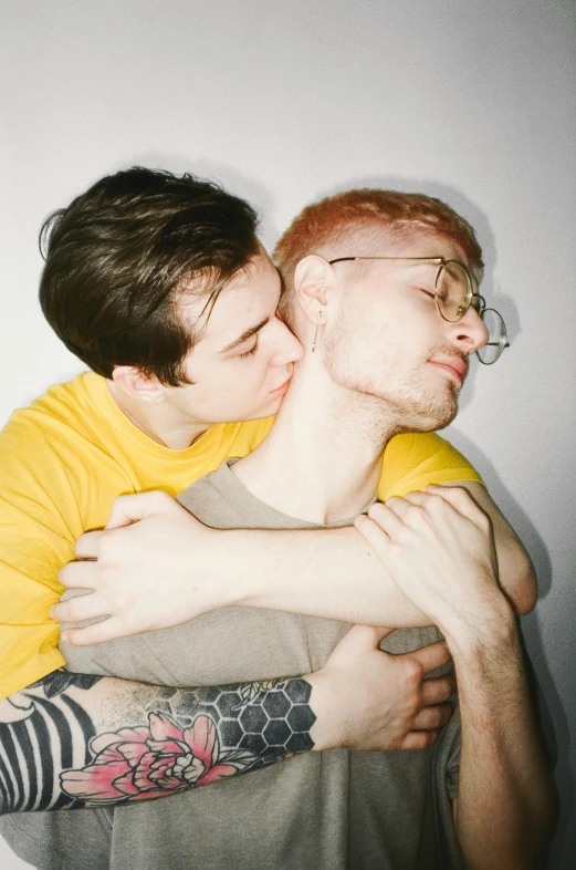 a couple of men standing next to each other, a polaroid photo, by Jessie Alexandra Dick, hugging and cradling, albino, mustard, structure : kyle lambert