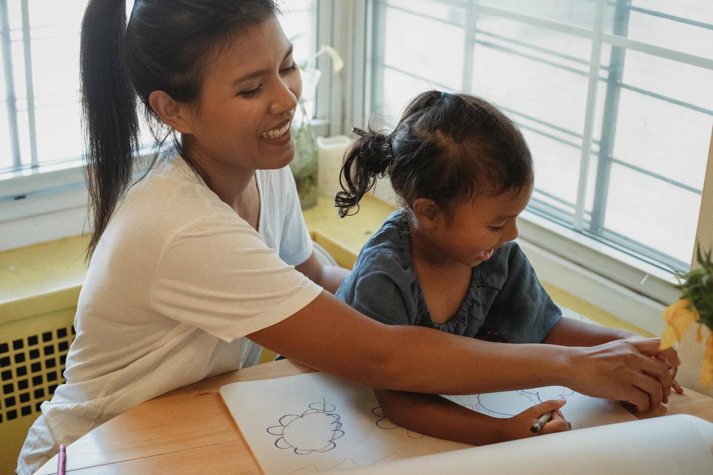 a woman sitting at a table with a child, a child's drawing, pexels contest winner, pokimane, very excited, asian female, nursing