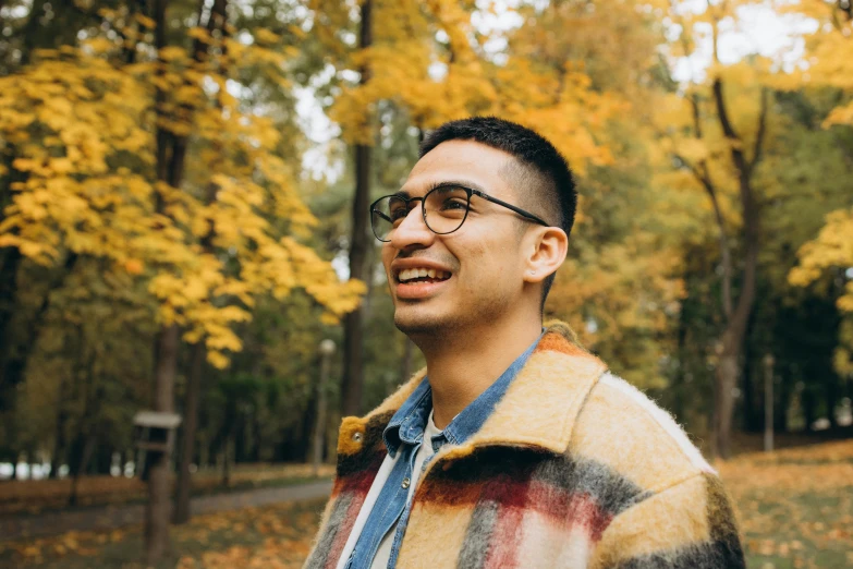 a man wearing glasses standing in a park, by Carey Morris, pexels contest winner, mutahar laughing, autumnal, non-binary, enes dirig