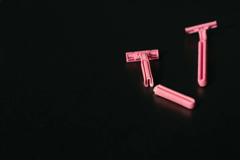 a pair of pink razors sitting on top of a black surface, unsplash, plasticien, color footage, thc, small blond goatee, tubes