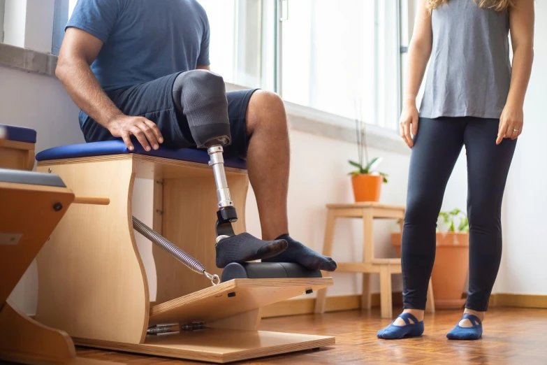 a man sitting on top of a wooden bench next to a woman, prosthetic leg, hedonic treadmill, brown, unblur