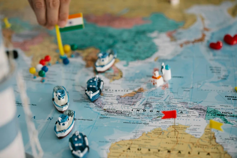 a close up of a toy boat on a map, by Julia Pishtar, pexels contest winner, india, playing games, varying locations, navy