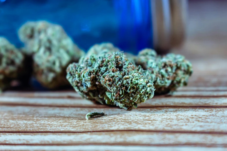 a bunch of marijuana sitting on top of a wooden table, a portrait, by Julia Pishtar, unsplash, blue, nug pic, high quality image”, bending down slightly