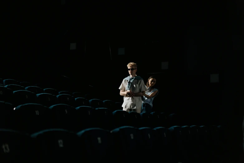 a couple of people standing next to each other in a dark room, a picture, unsplash contest winner, hyperrealism, sitting in a movie theater, cinematic morning light, high quality photo, \!cinestill 50d! film photo