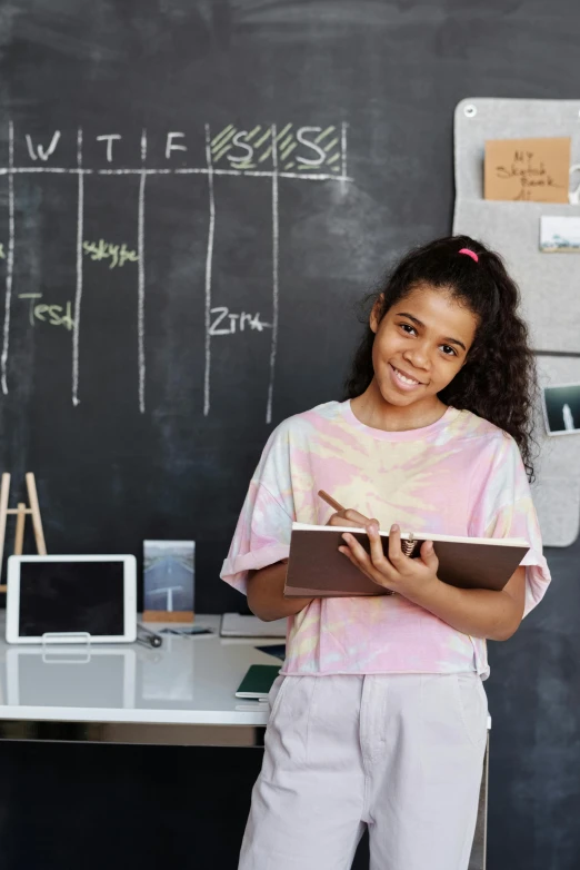 a girl standing in front of a blackboard holding a book, a digital rendering, pexels contest winner, black teenage boy, integrating with technology, and, teacher