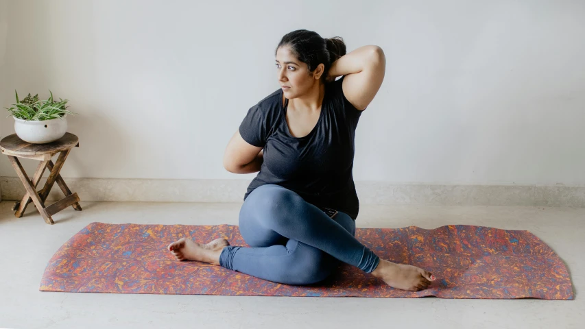 a woman sitting on top of a yoga mat, pexels contest winner, hurufiyya, arms to side, vinayak, slightly overweight, indigo