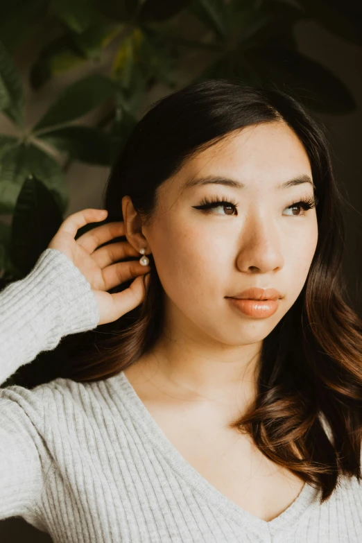 a woman standing in front of a potted plant, inspired by Ruth Jên, trending on pexels, renaissance, wearing pearl earrings, asian face, grey, earring