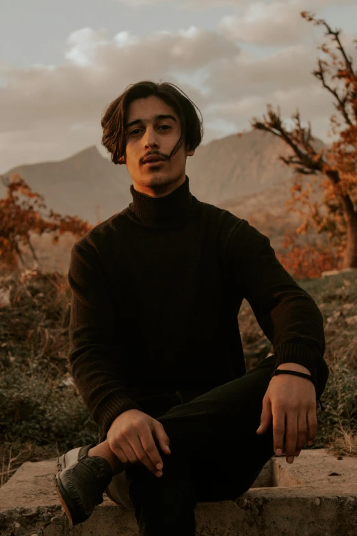 a man sitting on a rock in the desert, an album cover, pexels contest winner, wearing turtleneck, with mustache, non binary model, sayem reza