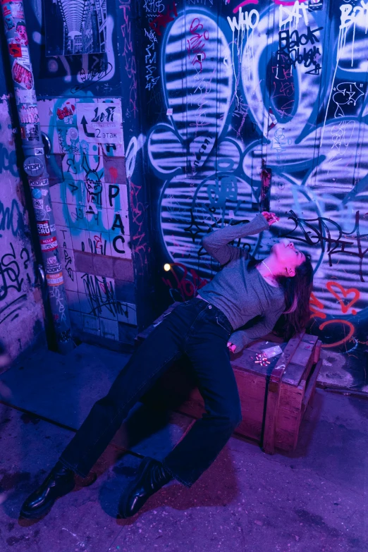 a person laying on the ground in front of a graffiti covered wall, inspired by Nan Goldin, happening, in a cyberpunk themed room, performance, drunk, instagram picture