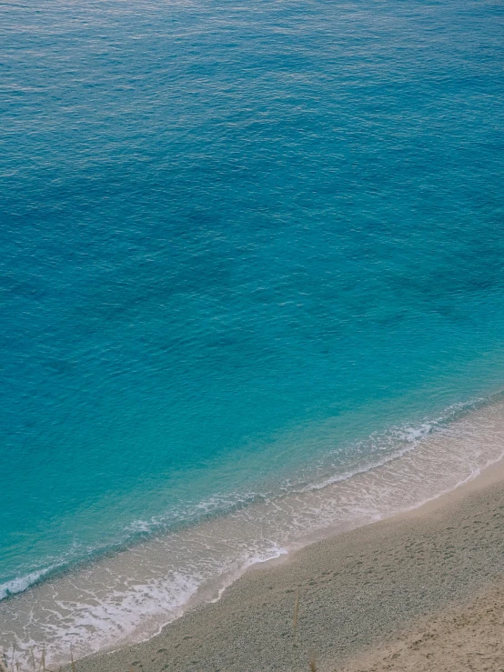 a couple of umbrellas sitting on top of a sandy beach, sapphire waters below, unsplash 4k, gulf of naples, brown and cyan color scheme