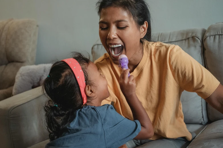 a woman sitting on a couch brushing a little girl's teeth, pexels contest winner, hurufiyya, ice cream cone, aboriginal capirote, excited facial expression, purple