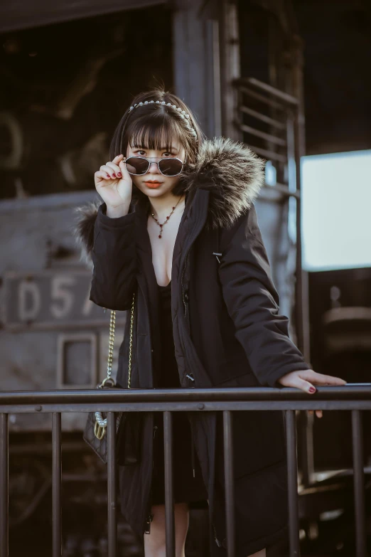 a woman standing on a balcony talking on a cell phone, an album cover, inspired by Elsa Bleda, trending on pexels, international gothic, cyberpunk sunglasses, asian girl, black fur, lone girl waiting for the train