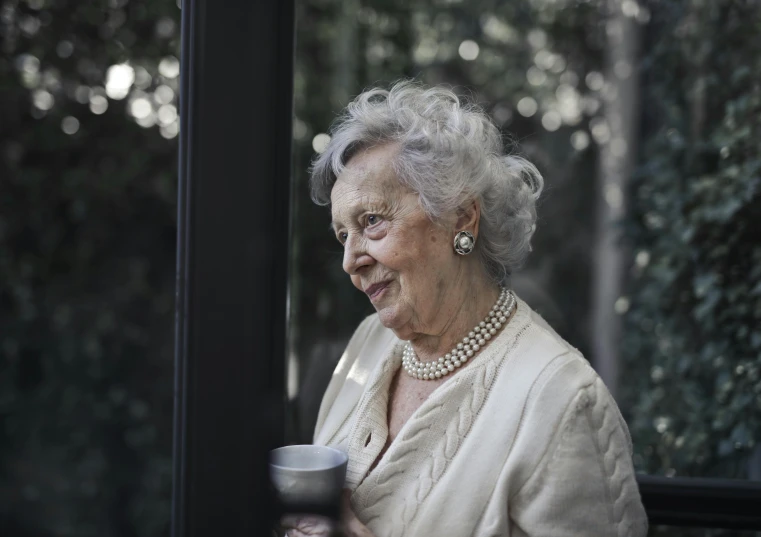 an older woman holding a cup of coffee, a portrait, pexels contest winner, looking outside, well - dressed, ((portrait)), nature outside