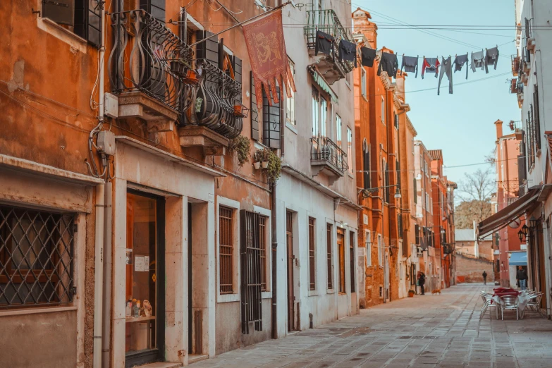 a narrow street with clothes hanging out to dry, a photo, pexels contest winner, renaissance, burnt sienna and venetian red, early evening, youtube thumbnail, view from the street