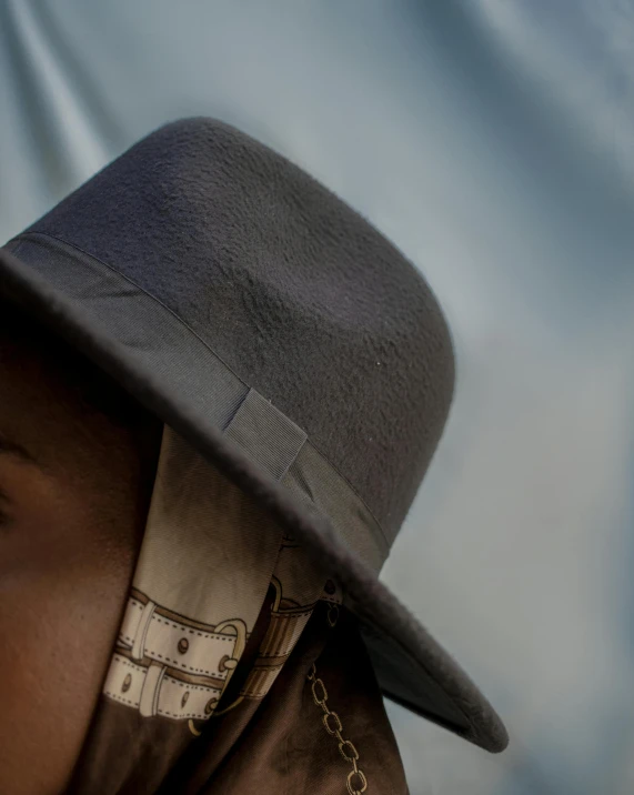 a close up of a person wearing a hat, an album cover, dark grey skin, background image, blue and grey, waist - shot