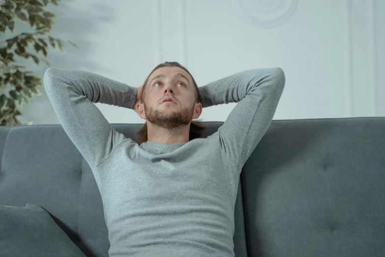 a man sitting on a couch with his hands behind his head, by Adam Marczyński, pexels contest winner, renaissance, grey, animation, casual pose, pondering