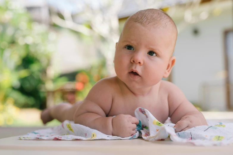 a close up of a baby laying on a table, unsplash, happening, wearing a towel, confident looking, may gibbs, super high resolution