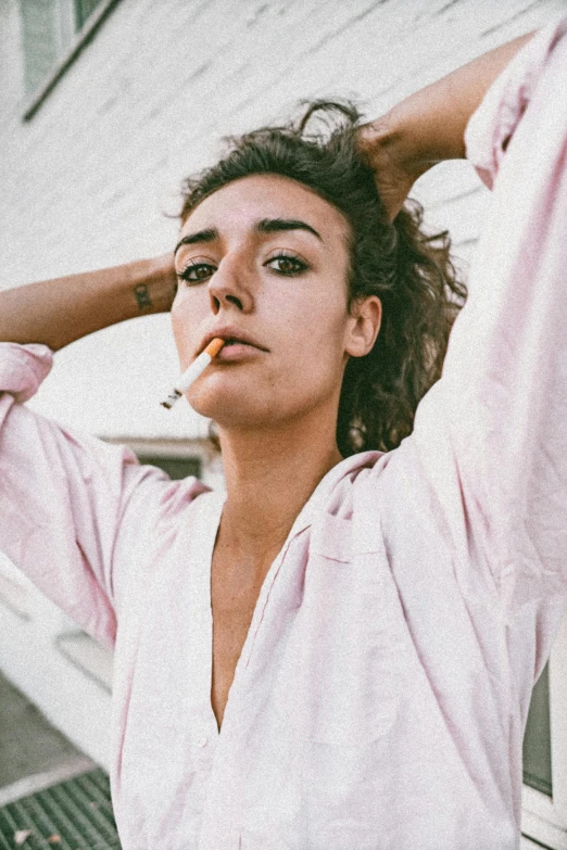 a woman in a pink shirt smokes a cigarette, an album cover, trending on unsplash, antipodeans, thick bushy straight eyebrows, robert sheehan, female streetwear blogger, wearing white pajamas