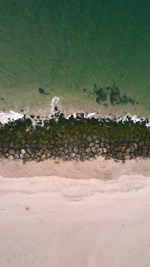 an aerial view of a beach and the ocean, inspired by Andreas Gursky, pexels, gradient green black, rocks), near a jetty, drone footage