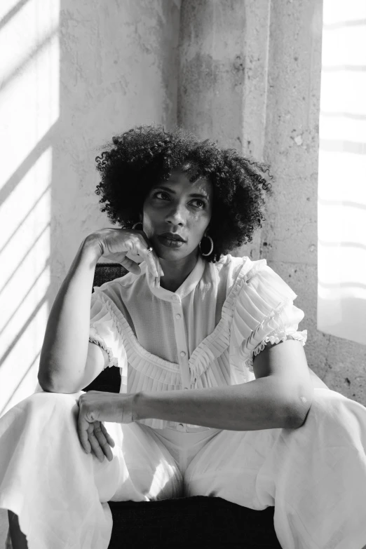 a black and white photo of a woman sitting on a chair, pexels contest winner, black arts movement, curly afro, wearing white cloths, square, promotional image