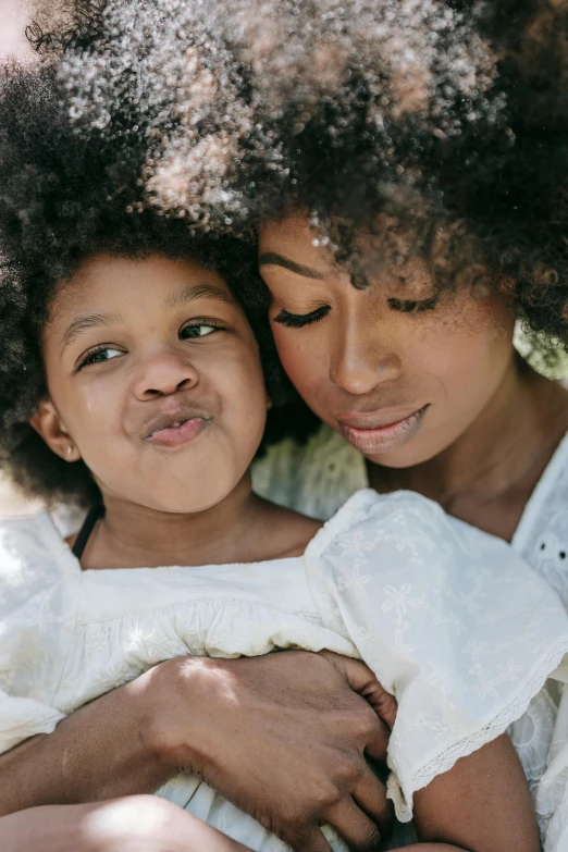 a woman holding a child in her arms, by Lily Delissa Joseph, pexels contest winner, long afro hair, closeup of an adorable, full lips, varying ethnicities