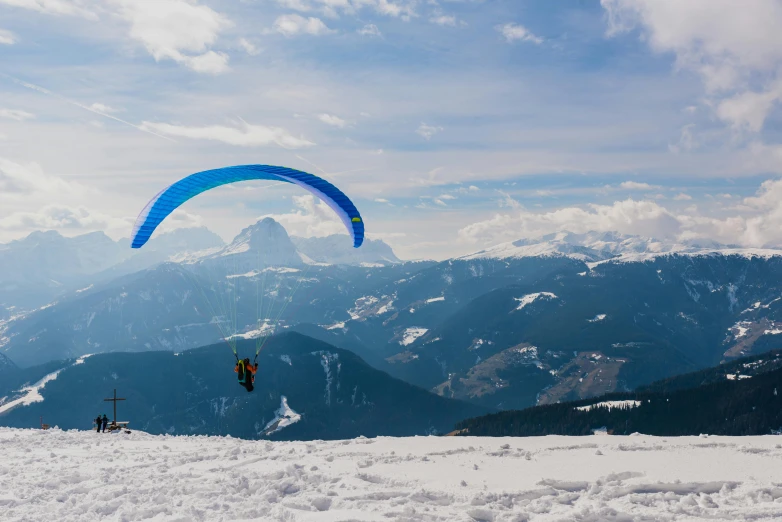 a person flying a kite on top of a snow covered slope, in the dolomites, profile image, blue print, parachutes