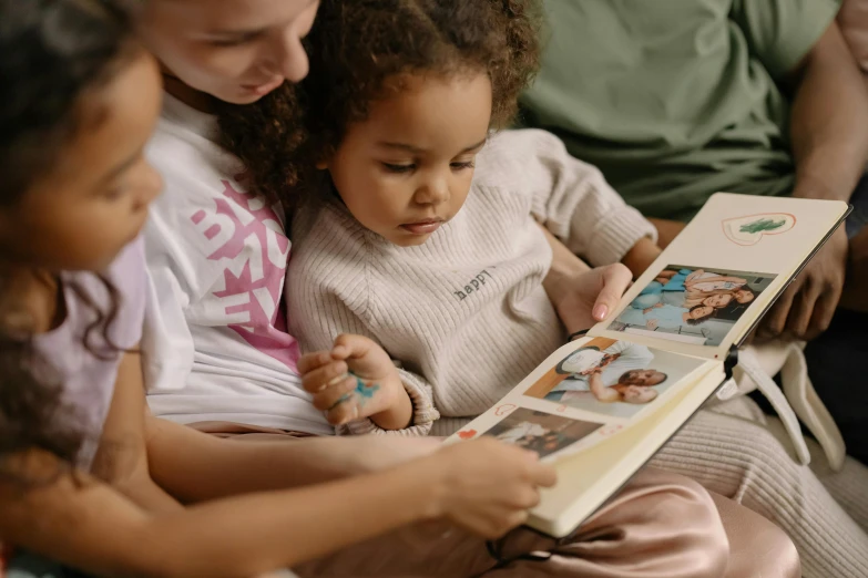 a group of children sitting on a couch reading a book, a storybook illustration, by Emma Andijewska, pexels contest winner, closeup portrait shot, scrapbook, toddler, three