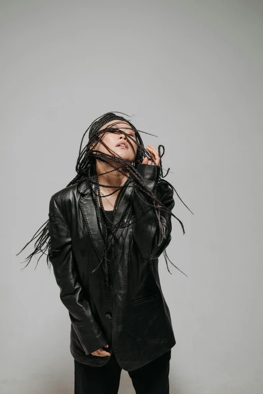 a woman in a black leather jacket and leggings, an album cover, trending on pexels, dreadlock black hair, gongbi, agnes cecile, with his hands in his hair