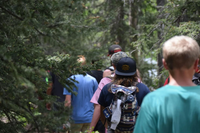 a group of people walking through a forest, a photo, wyoming, summer camp, facing away from camera, educational