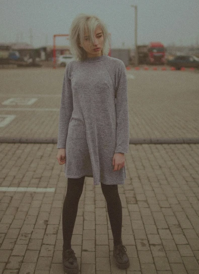 a woman is standing in a parking lot, a picture, inspired by Elsa Bleda, realism, grey sweater, women full body, organic dress, rectangle