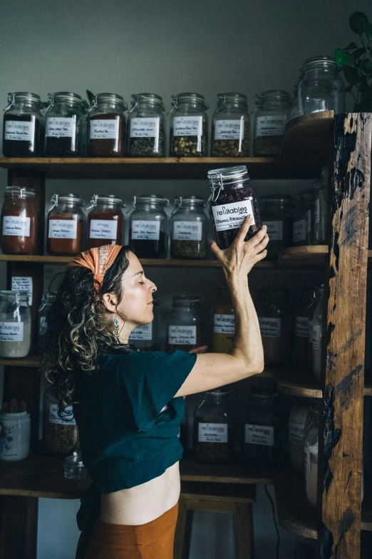 a woman standing in front of a shelf filled with jars, cottage hippie naturalist, sustainability, profile image, dwell