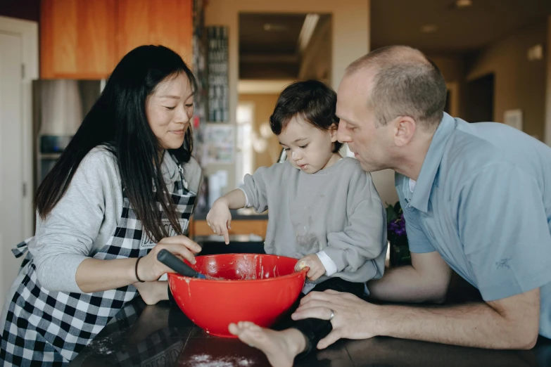 a group of people standing around a red bowl, in the kitchen, profile image, fatherly, professional image