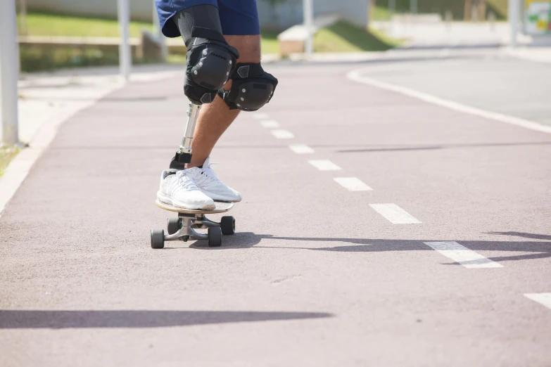 a man riding a skateboard down a street, a picture, artificial limbs, no text, wearing knee and elbow pads, innovation
