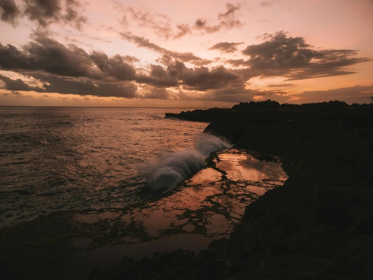 a large body of water with a sunset in the background, by Daniel Seghers, pexels contest winner, cliff side, clouds and waves, bali, fine art print