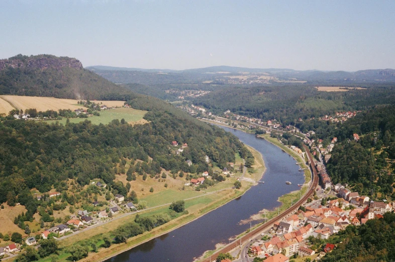 a river running through a lush green valley, by Werner Gutzeit, pexels contest winner, renaissance, in the foreground a small town, aerial footage, 1980s photo, slide show
