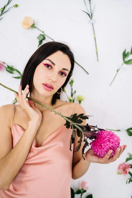 a woman in a pink dress holding a pink flower, flowers in her dark hair, non binary model, promo image, ukrainian