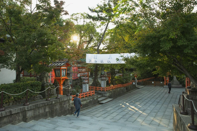 a person walking down a set of stairs, sōsaku hanga, white and orange, shrines, the sun is shining. photographic