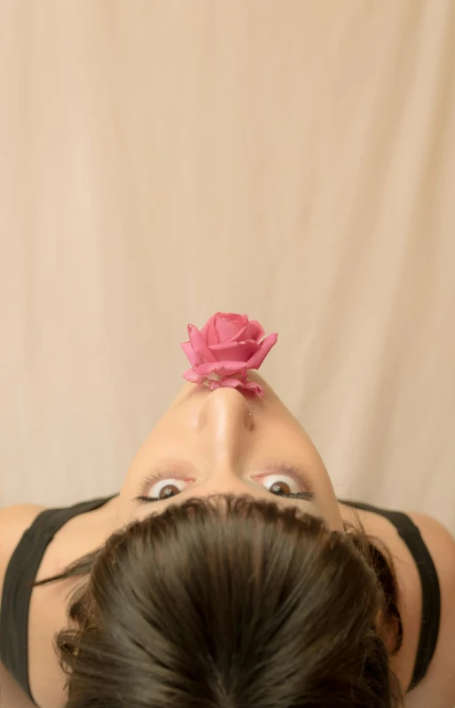 a woman laying on a bed with a pink flower in her hair, by Kristin Nelson, unsplash, hyperrealism, scary angry pose, hanging upside down, square nose, growing out of a giant rose