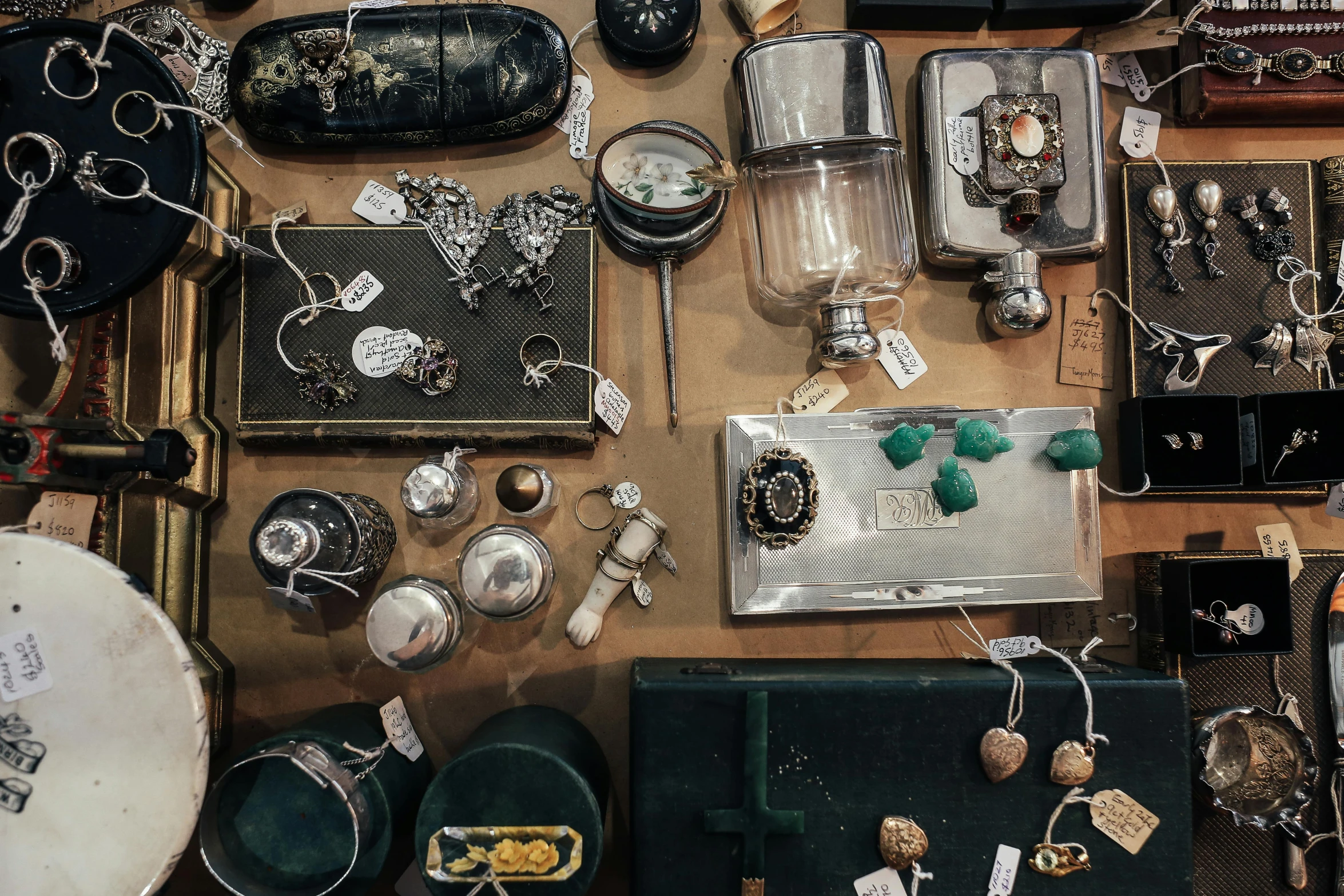 a table topped with lots of assorted items, by Frederik Vermehren, trending on unsplash, assemblage, jewelry engraved in scarab, flasks, chrome hearts, thumbnail