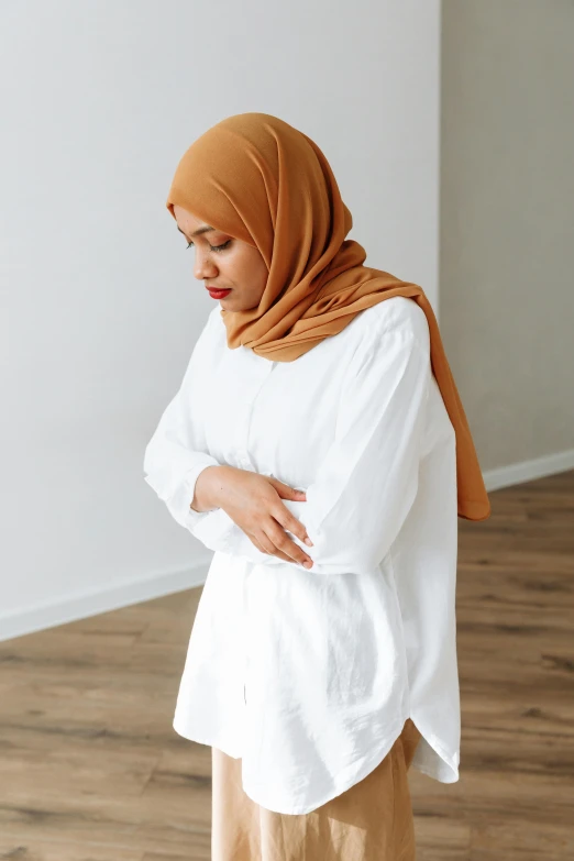 a woman in a white shirt and tan pants, inspired by Nazmi Ziya Güran, trending on pexels, hurufiyya, head scarf, concerned, collection product, pregnancy