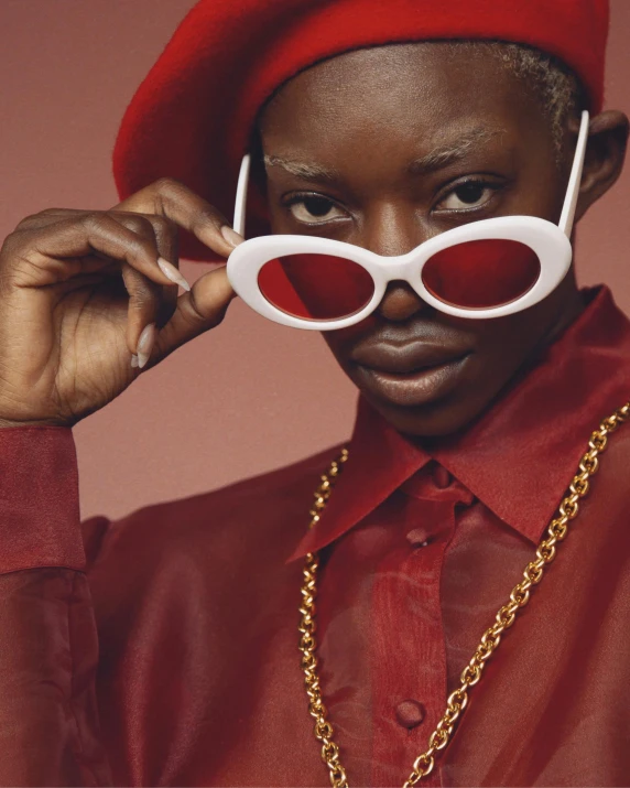 a close up of a person wearing a hat and sunglasses, an album cover, inspired by Jean-Yves Couliou, trending on unsplash, afrofuturism, dressed in red velvet, nonbinary model, red tailcoat, off - white collection