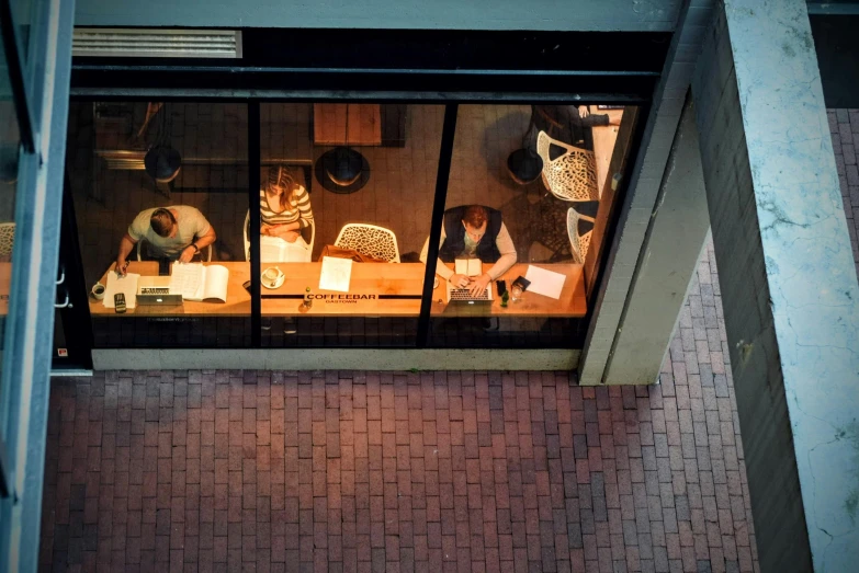 a group of people sitting at a table in front of a window, pexels contest winner, lit from above, backrooms office space, night outside, full daylight