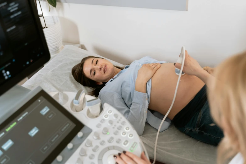 a woman laying on top of a bed next to a computer, by Évariste Vital Luminais, trending on pexels, figuration libre, membrane pregnancy sac, medical machinery, background image