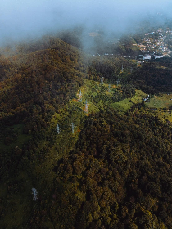 an aerial view of a small town in the mountains, a matte painting, pexels contest winner, sumatraism, powerlines, meadow in the forest, aerial view cinestill 800t 18mm, hill with trees