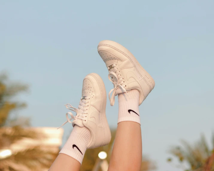 a person laying on the ground with their feet in the air, trending on pexels, wearing white sneakers, uniform off - white sky, nike logo, pastel shades