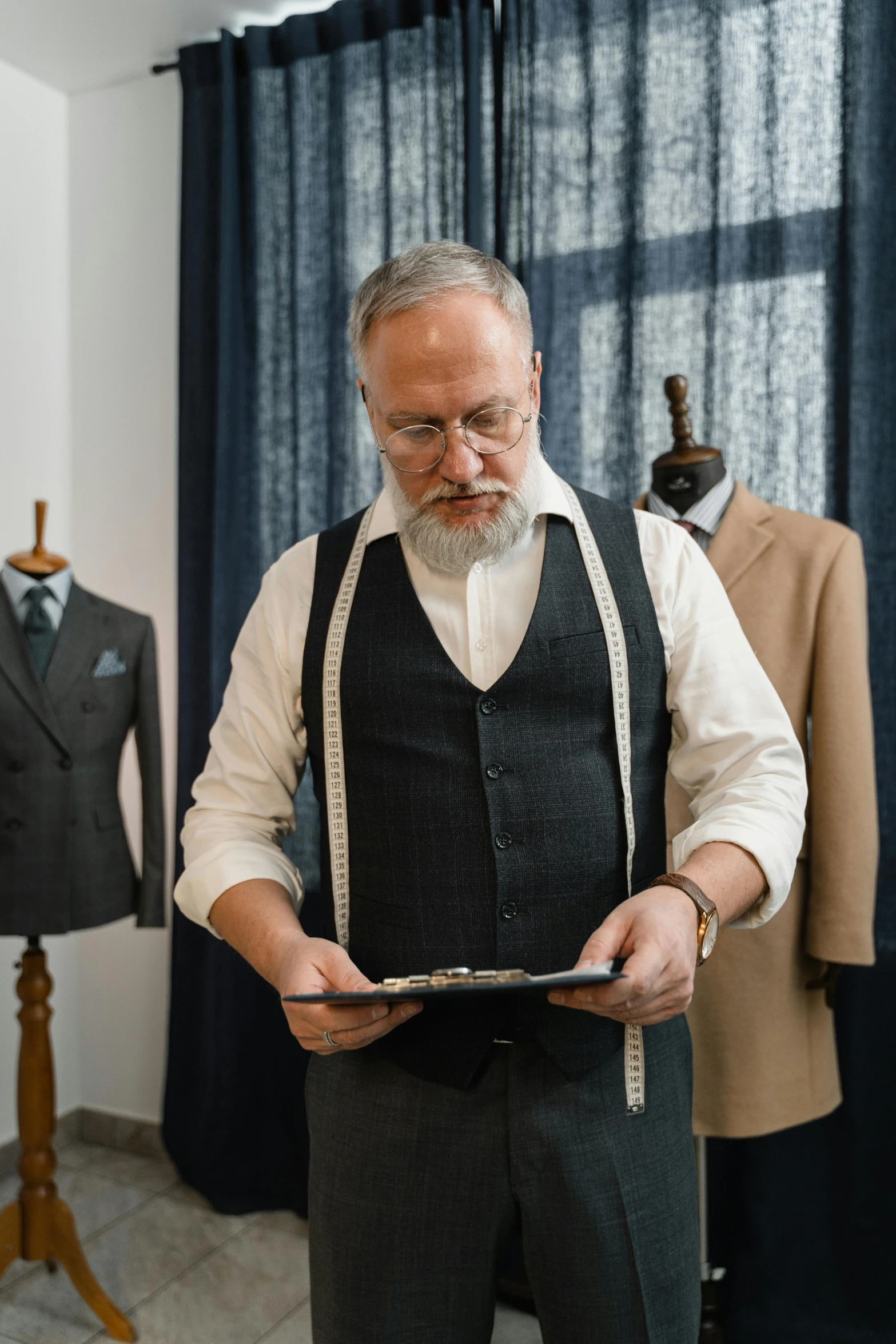 a man standing in front of a mannequin holding a tablet, wearing suit vest, overalls and a white beard, look at all that detail, luxurious suit