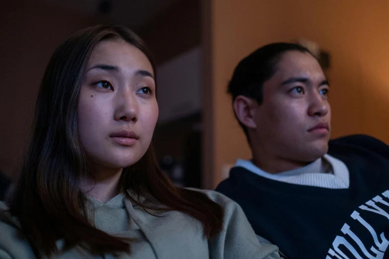 a man and a woman sitting next to each other, inspired by Zhang Xiaogang, trending on pexels, hyperrealism, japanese live-action movie, proud serious expression, watching tv, ethnicity : japanese